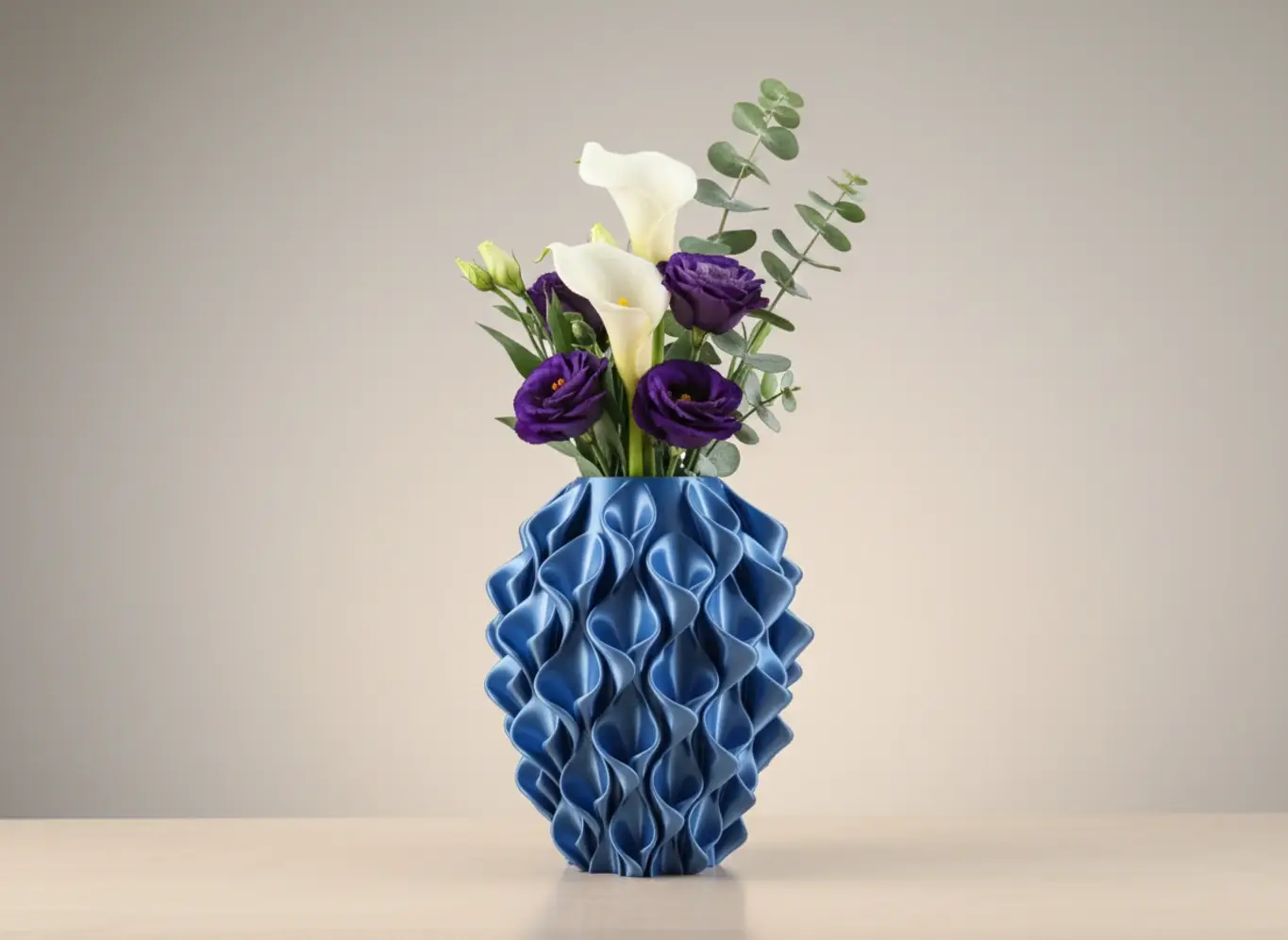 Sügavsinine 3D-prinditud lainemustriga vaas, milles on elegantsed valged ja lillad lilled, heledal laual